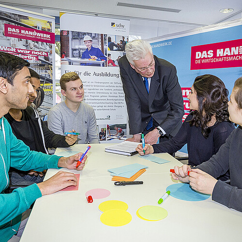 Fünf Jugendliche und Klosterkammer-Präsident Hans-Christian Biallas sind um einen Tisch herum gruppiert.