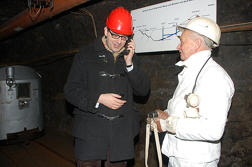 Zwei Männer mit Helmen stehen im Klosterstollen Barsinghausen unter Tage.